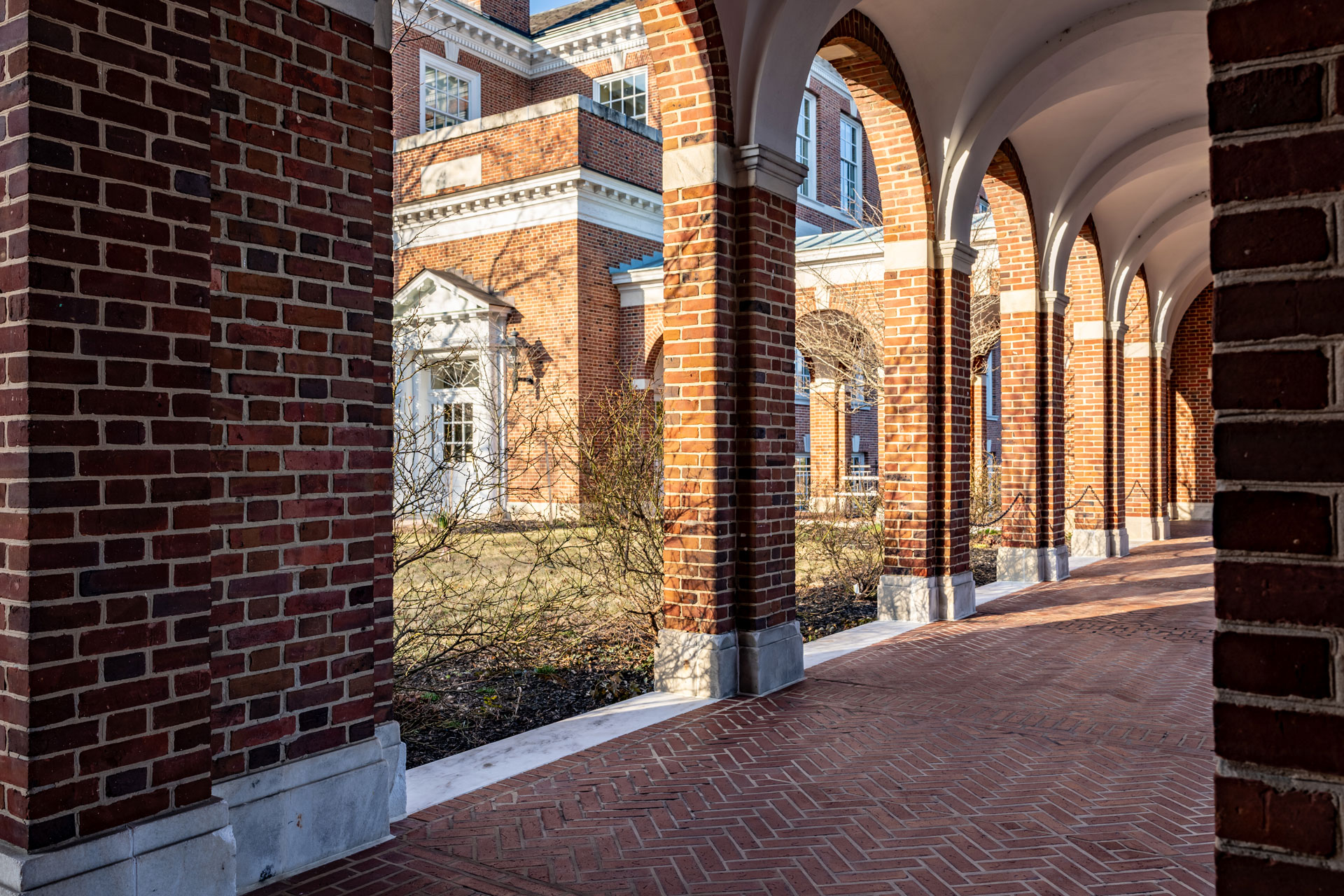 By-the-Numbers–The-Trump-Administrations-Assault-on-Universities Old arched brick walkway with brick pillars.