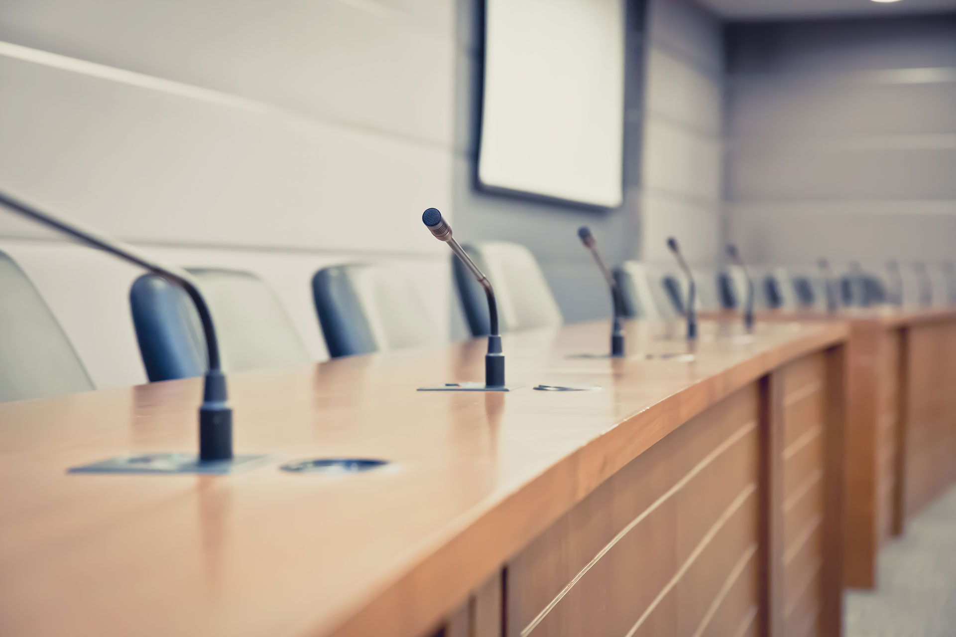 From-Shared-Governance-to-Scared-Governance An empty meeting room with microphones.