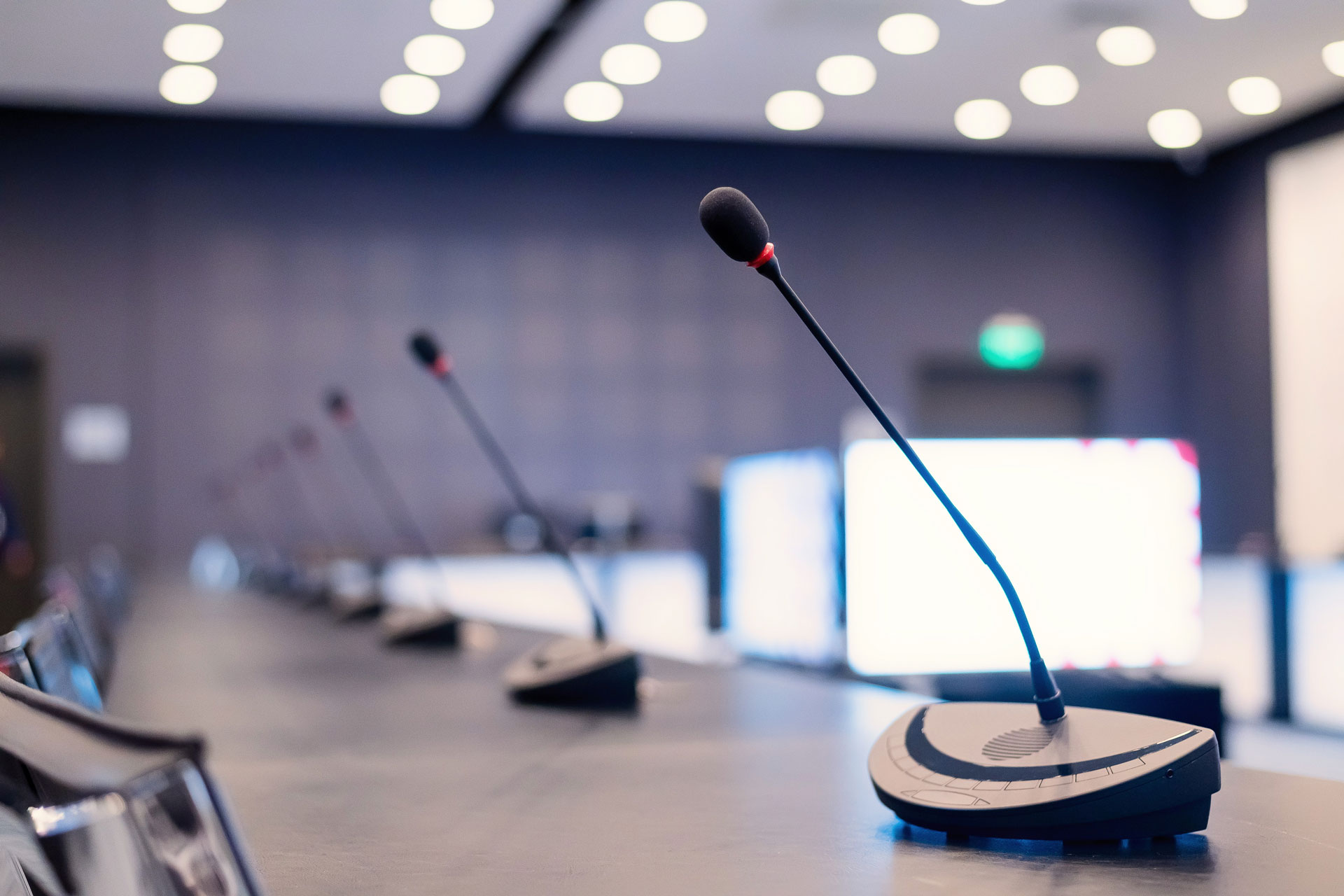 Board-Guide–Governance-Self-Assessment Close-up of microphones in an empty meeting room at a press conference.