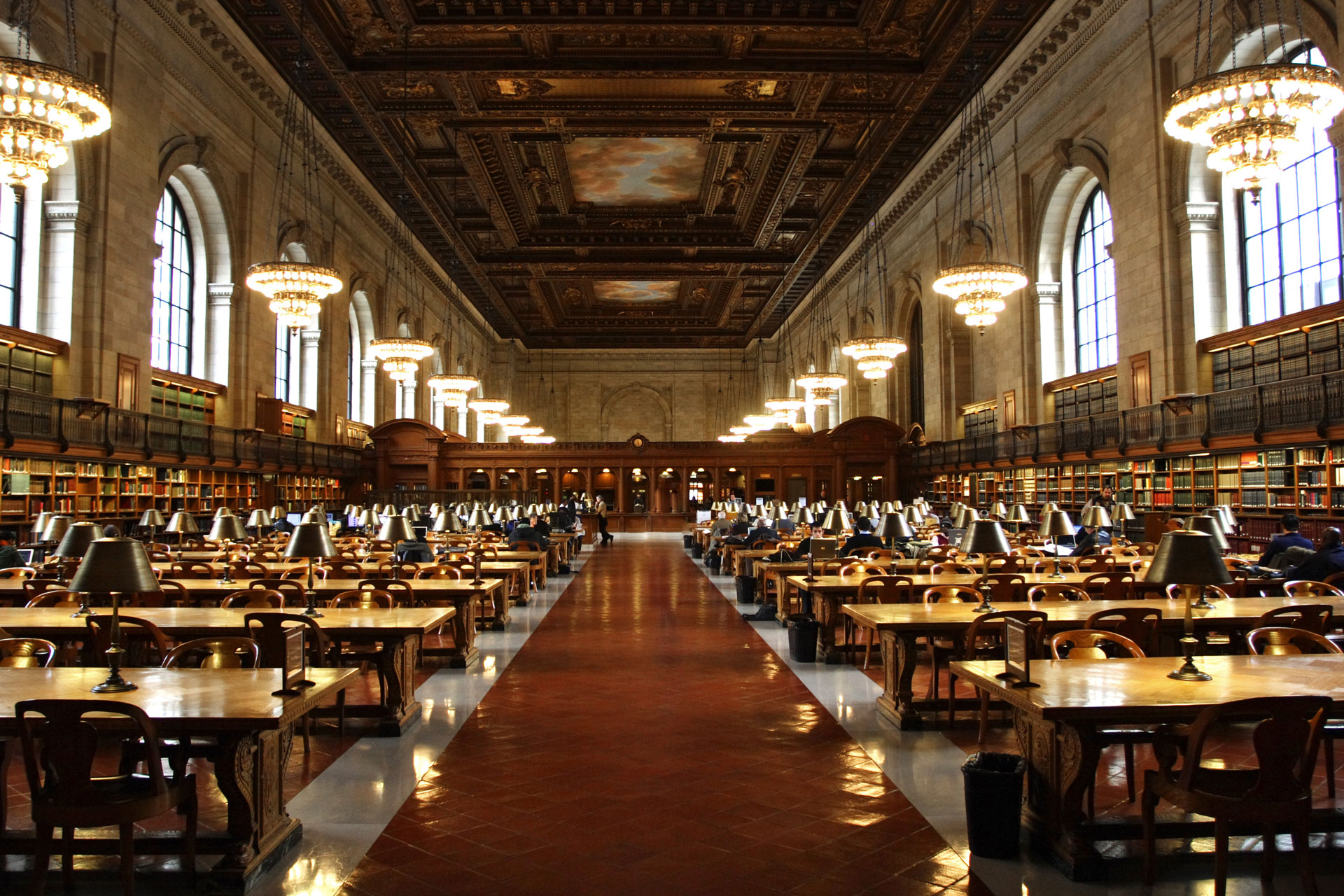 Large college library with two columns of study tables on either side of a walkway.