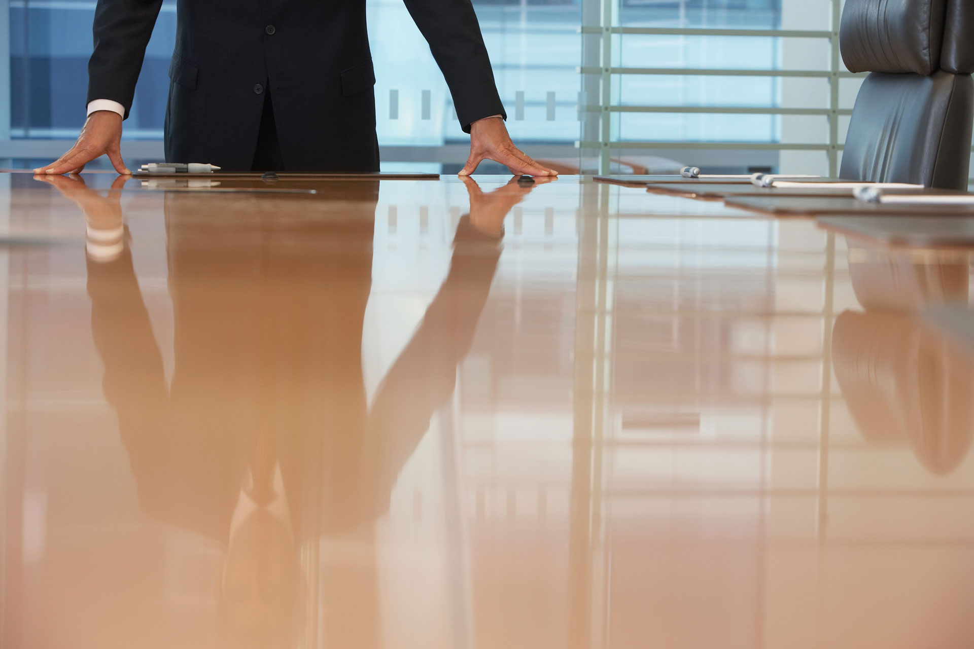 Implementing-Mission-Centered-Governance-Under-Pressure A person leaning forward on a table in a conference room.