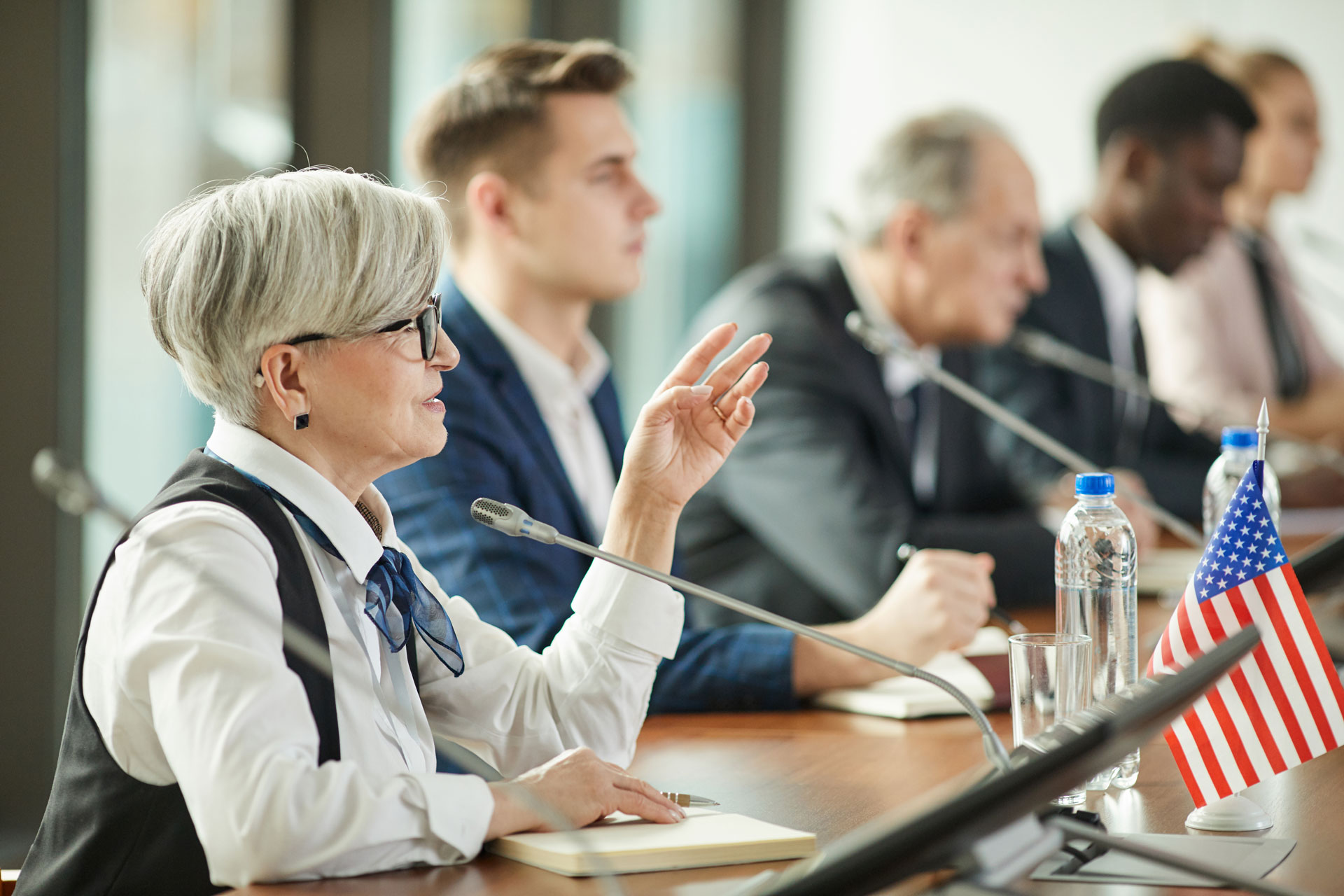 Female Board Member sitting at the table and speaking at conference.