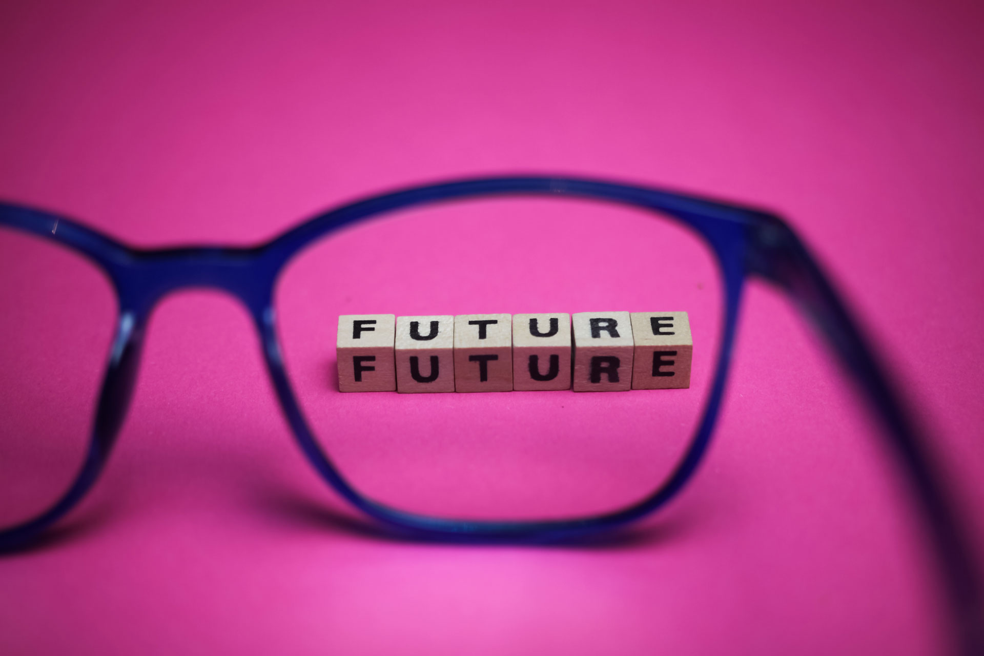 The right frame of a pair of glasses framing scrabble pieces that spell out the word 'future'