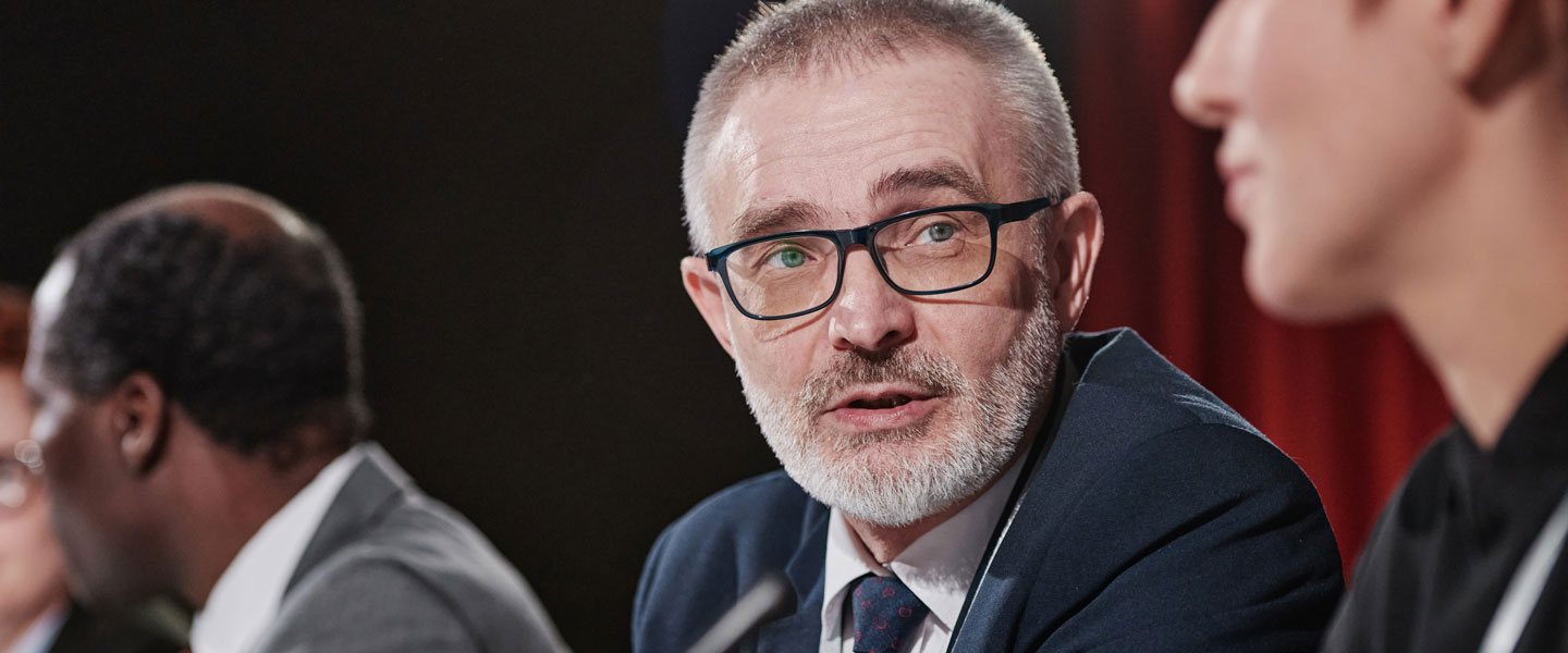 Man in eyeglasses discussing with his partners at table during meeting.